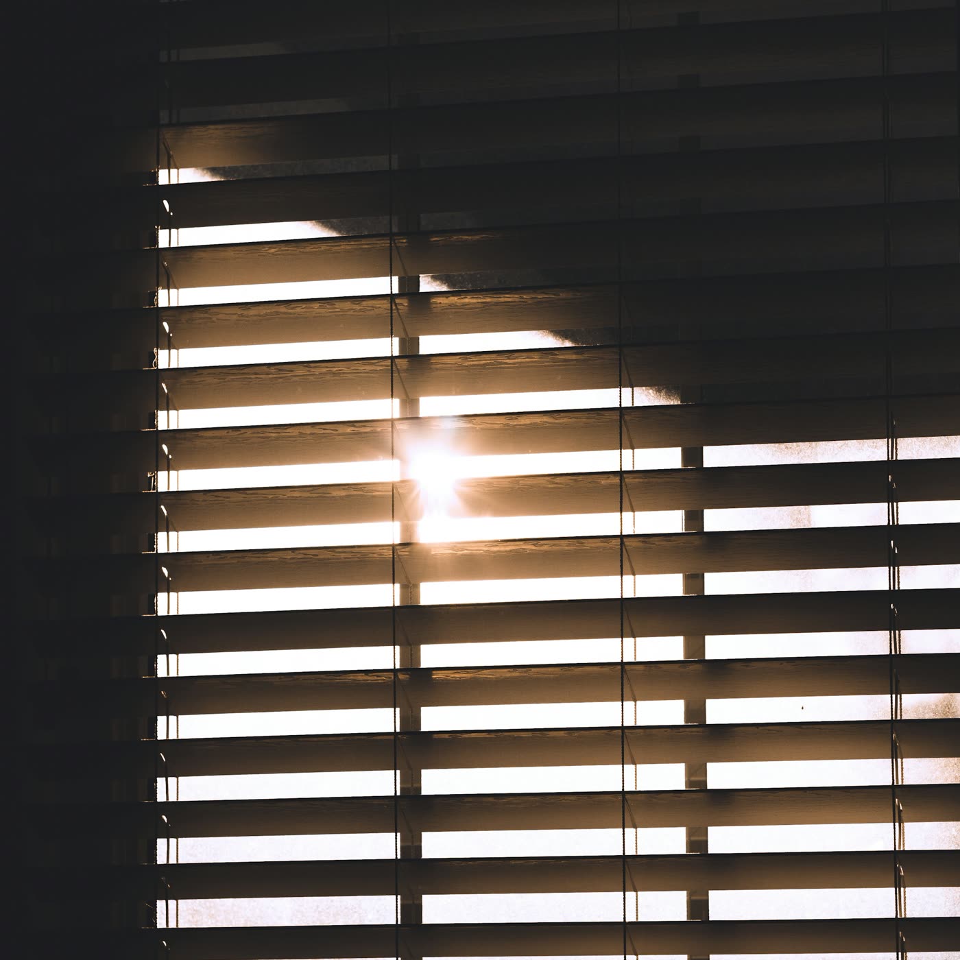Bright sunlight streaming through window blinds on a hot afternoon